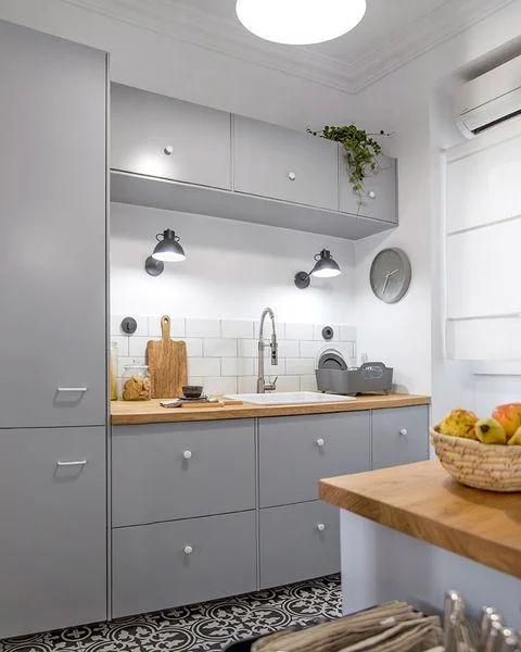 Cocina gris claro revestimiento blanco y mesada de madera